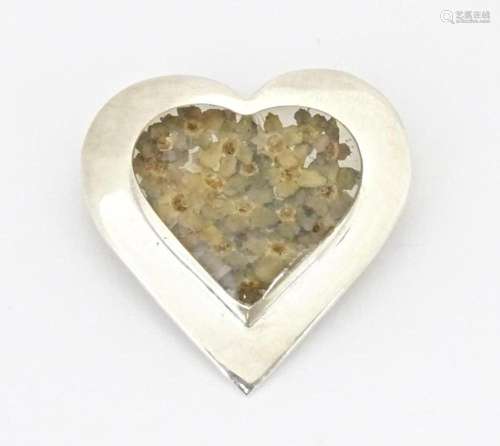 A silver heart shaped brooch with forget me not flower decor...