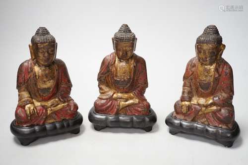 A set of three Chinese polychrome lacquered wood seated figu...