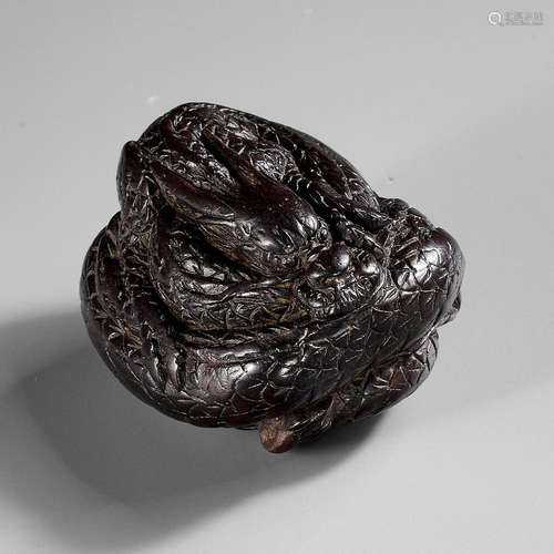 A SUPERB DARK WOOD NETSUKE OF A COILED DRAGON, ATTRIBUTED TO...