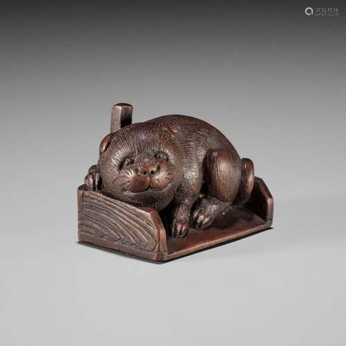 KOKEI: A WOOD NETSUKE OF A PUPPY INSIDE A DUSTPAN