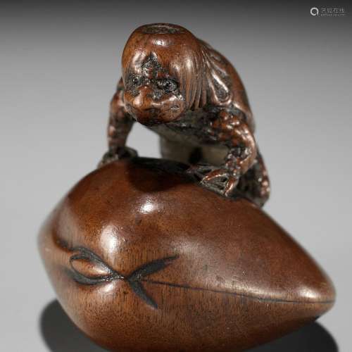 SUKETADA: A FINE WOOD NETSUKE OF A KAPPA TRAPPED BY A CLAM