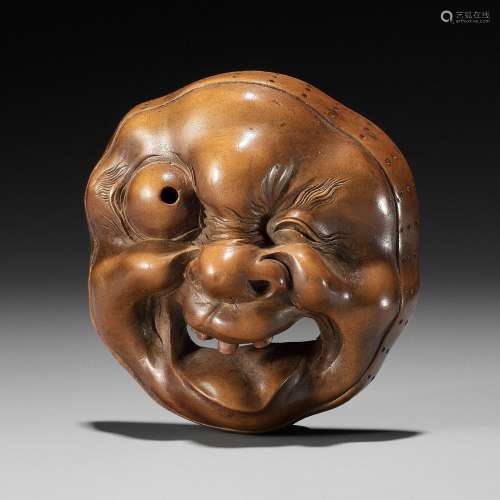 A LARGE AND SUPERB WOOD MASK NETSUKE OF A GROTESQUELY GRIMAC...