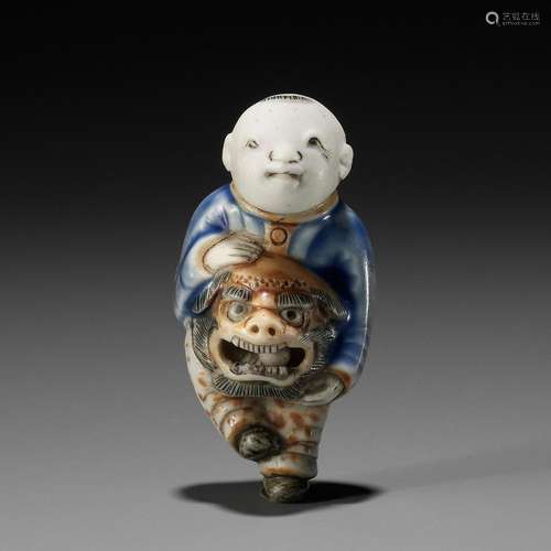 A HIRADO GLAZED PORCELAIN NETSUKE OF A BOY WITH SHISHIMAI MA...