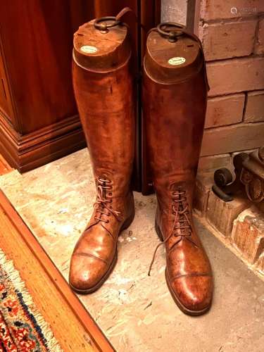 A pair of aged tan-leather riding boots with stretchers by M...