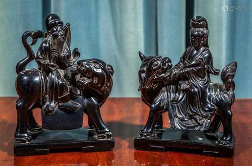 A pair of Chinese black lacquered carved wood figures of imm...