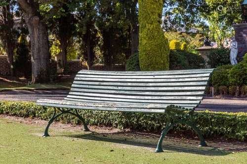 A pair of green painted slatted wood and cast-iron garden se...