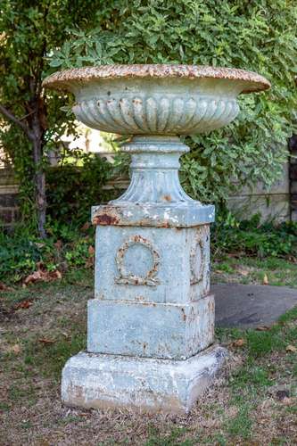 A large green painted cast-iron Classical Grecian urn on ped...