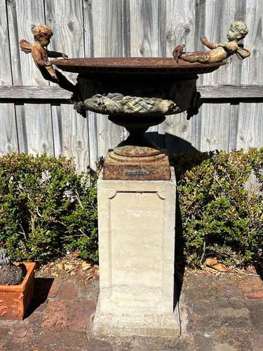 An elaborate cast-iron garden urn on modern reconstituted st...