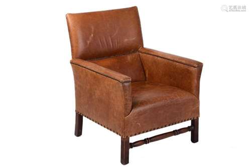 A deep-seated distressed tan leather-covered fireside armcha...