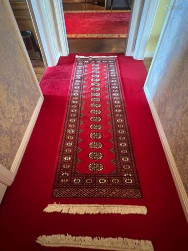 A modern red ground Persian Tekke design wool-pile runner 24...