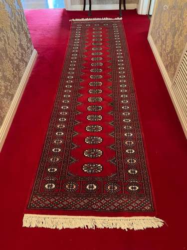 A modern red ground Persian Tekke design wool-pile runner 28...