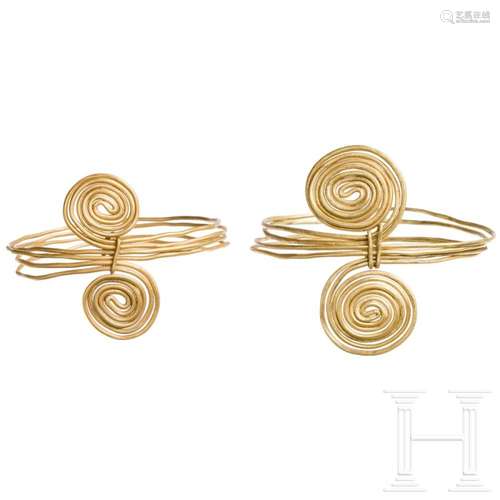 A pair of gold wire rings with four loops and spiral ends, l...