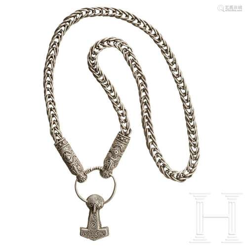 A silver necklace with animal head ends and Thor's hamme...