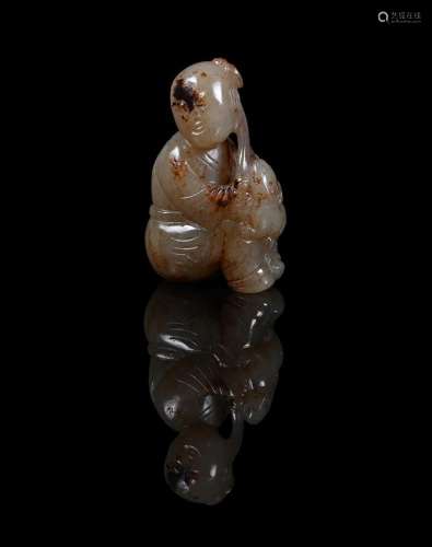 A Chinese celadon and brown jade carving of a boy and lion c...