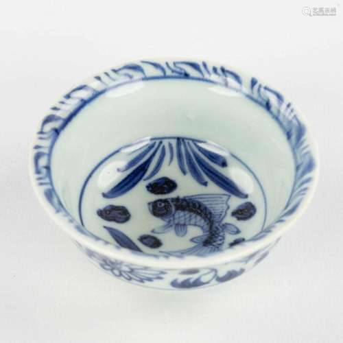 A small Chinese tea bowl with blue-white fish decor. Ming dy...