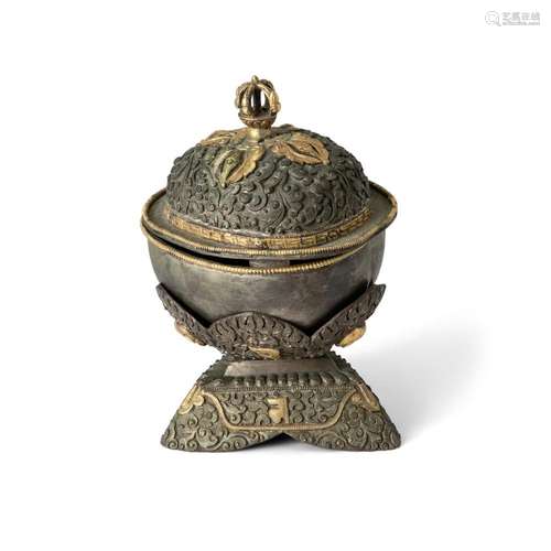 A Tibetan white metal and gilt ritual skull cup and cover wi...