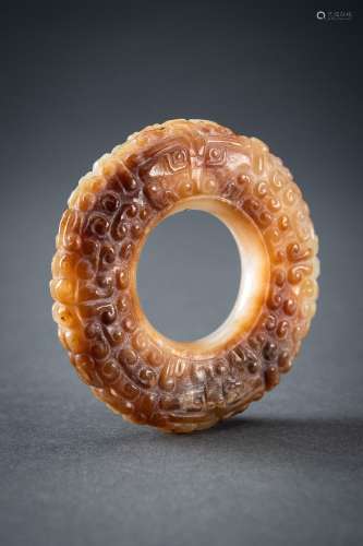 A WHITE AND RUSSET JADE ‘CURLS AND TAOTIE MASKS’ RING, HUAN,...
