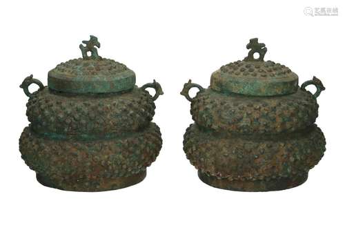 A pair of bronze lidded jars with handles in the sh