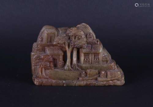 A soapstone group of a mountain village on a river with boat...