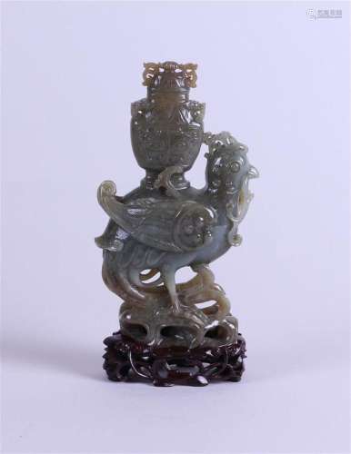 An olive-colored jade phoenix on a carved wooden base. China...