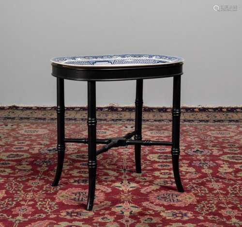 A blue and white Willow Pattern charger on an ebonized stand...