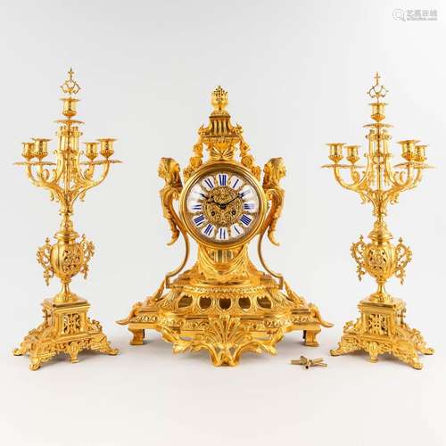 A three-piece mantle garniture clock and candelabra, gilt br...