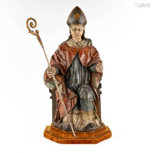 An antique wood sculpture of a saint with his staff and mitr...