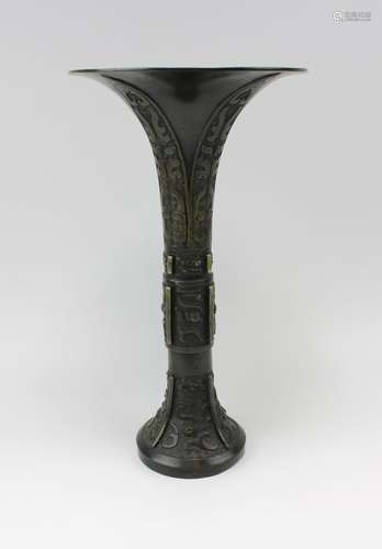 A tall Gu bronze vase with archaic-patterned relief