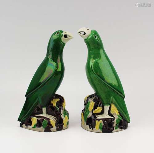 A pair of sancai biscuit-ware parrots on rocky bases