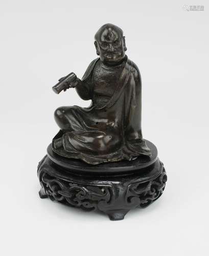 A small bronze figure of a Luohan on wooden base