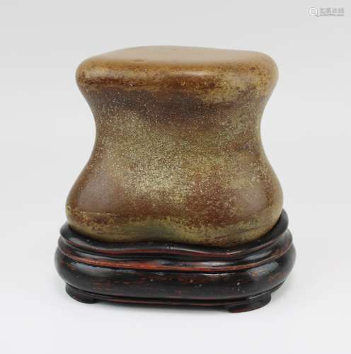 A Scholar rock, shaped as a vertibrae, wax stone on wooden s...