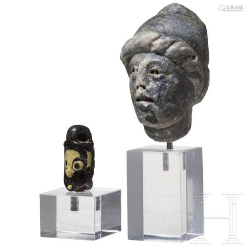 A stone head with Phrygian cap and a Phoenician glass head p...
