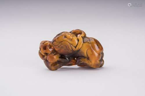 A RARE AMBER CARVING OF A BUDDHIST LION WITH BALL