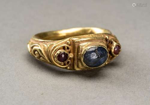 A GANDHARAN GOLD RING INLAID WITH SAPPHIRE AND TWO SMALL GAR...