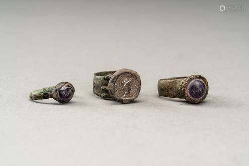 THREE PERSIAN BRONZE RINGS WITH AMETHYST INTAGLIOS AND A COI...