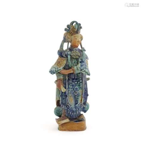 A Chinese Sancai style pottery figure holding a sc…