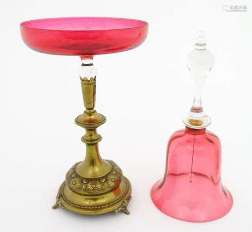 A cranberry clear glass bell together with a glass…