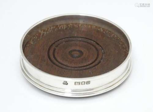 A small silver coaster with a turned wooden base, …