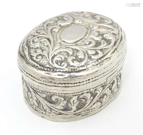 A white metal pill box of oval form with embossed …