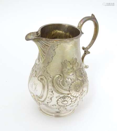 A Victorian silver jug with embossed floral decora…