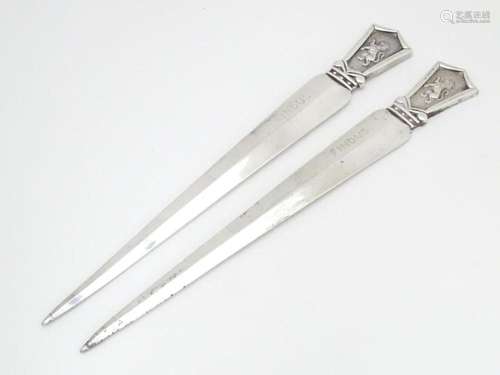 A pair of silver plate letter openers surmounted b…