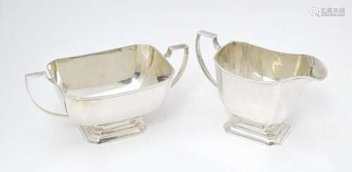 A white metal sugar bowl and milk jug. The jug app…