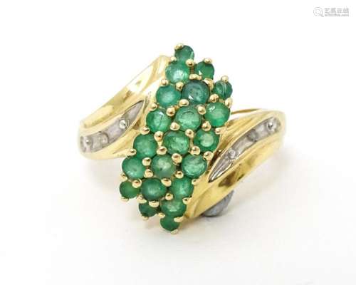 An 18ct gold ring set with emeralds, flanked by a …