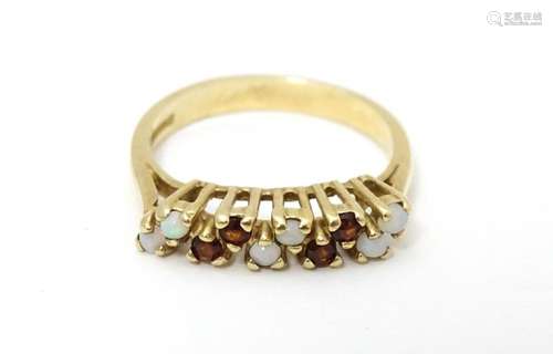 A 9ct gold ring set with opals and garnets. Ring s…