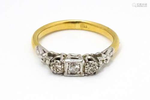 A gold ring set with trio of diamonds. Ring size a…