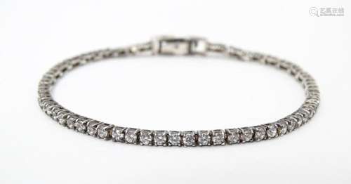 A silver tennis bracelet set with cubic zirconia. …