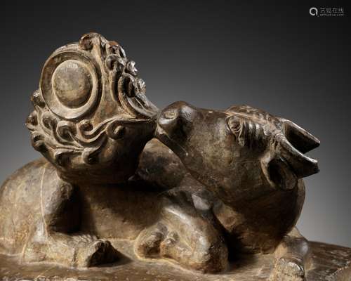 A LIMESTONE FIGURE OF A TWO-HORNED MYTHICAL BEAST, GAZING AT...