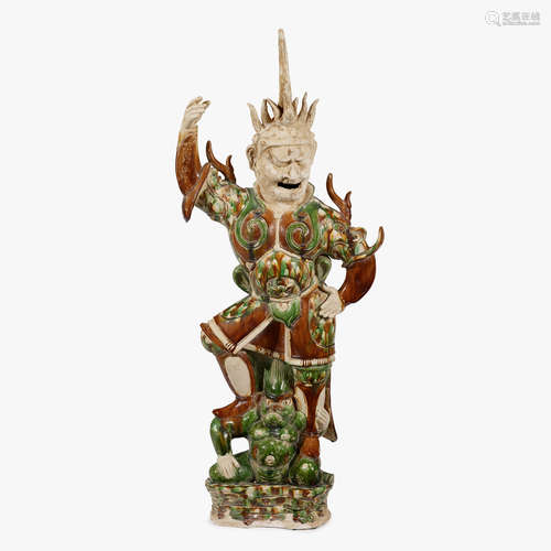 A Chinese sancai glazed pottery tomb guardian figure over a demon, tang dynasty