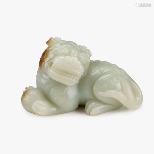 A Chinese celadon jade recumbent fu lion with brocade ball between paws,