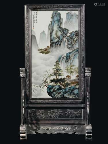 A large polychrome enammeled porcelain plaque depicting houses and mountain landscape with inscription on a wooden stand, China, early 20th century